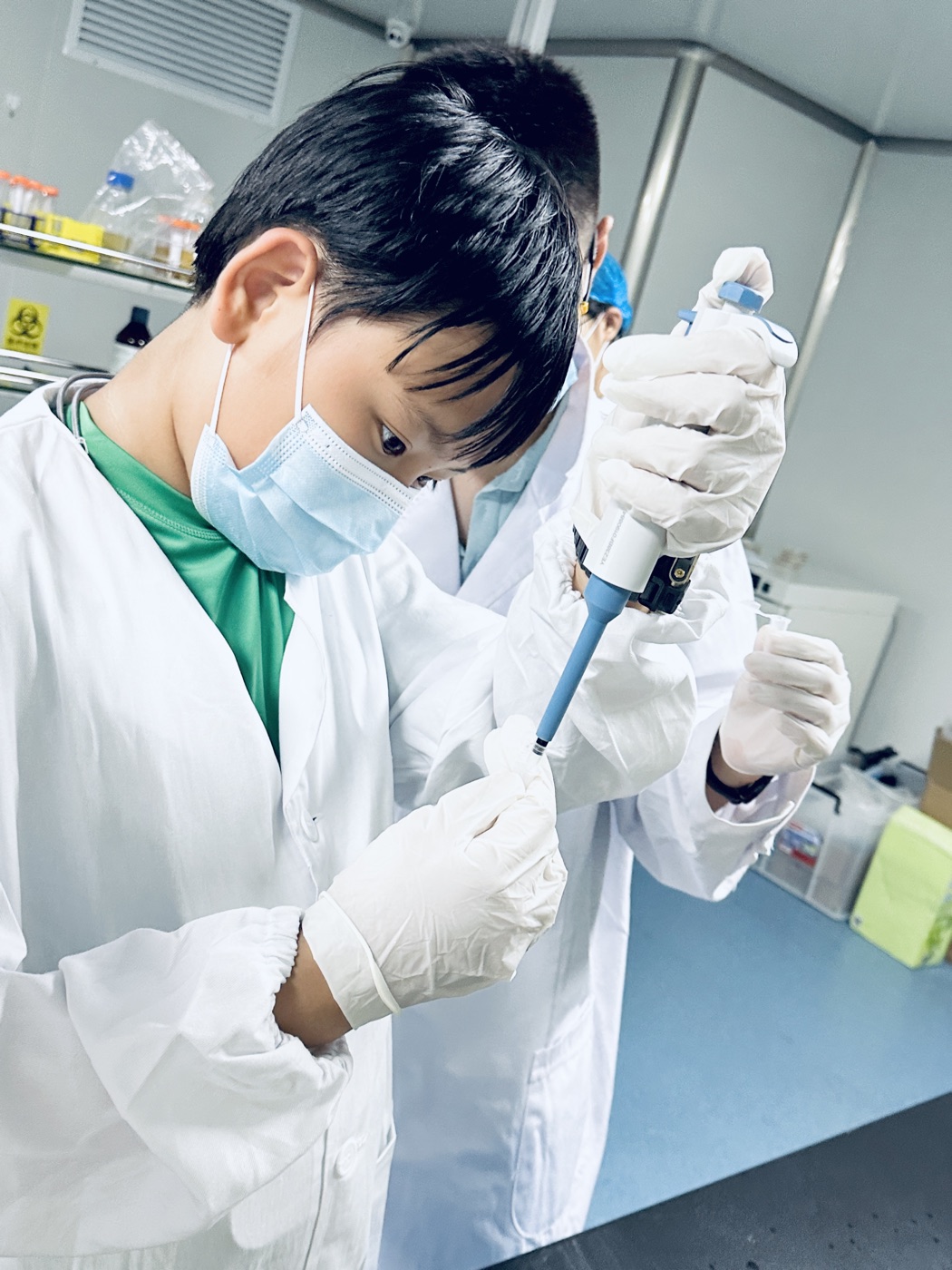 Alan Wang working in a science lab with a pipette